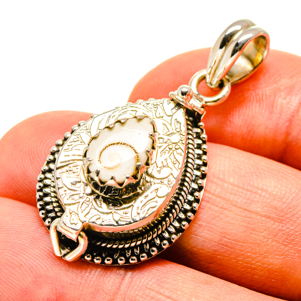 Sterling silver evil eye pendant close-up, white enamel-like center, textured engraved frame