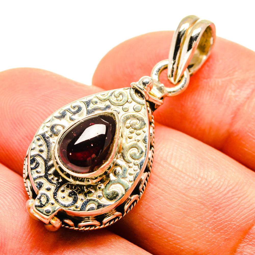 Ornate teardrop garnet pendant in sterling silver with dark red stone and gold-tone frame