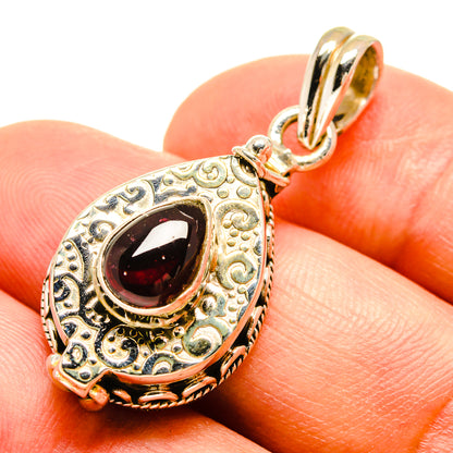 Ornate teardrop garnet pendant in sterling silver with dark red stone and gold-tone frame