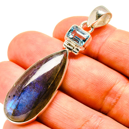 Sterling silver pendant closeup: blue topaz set above oval labradorite drop