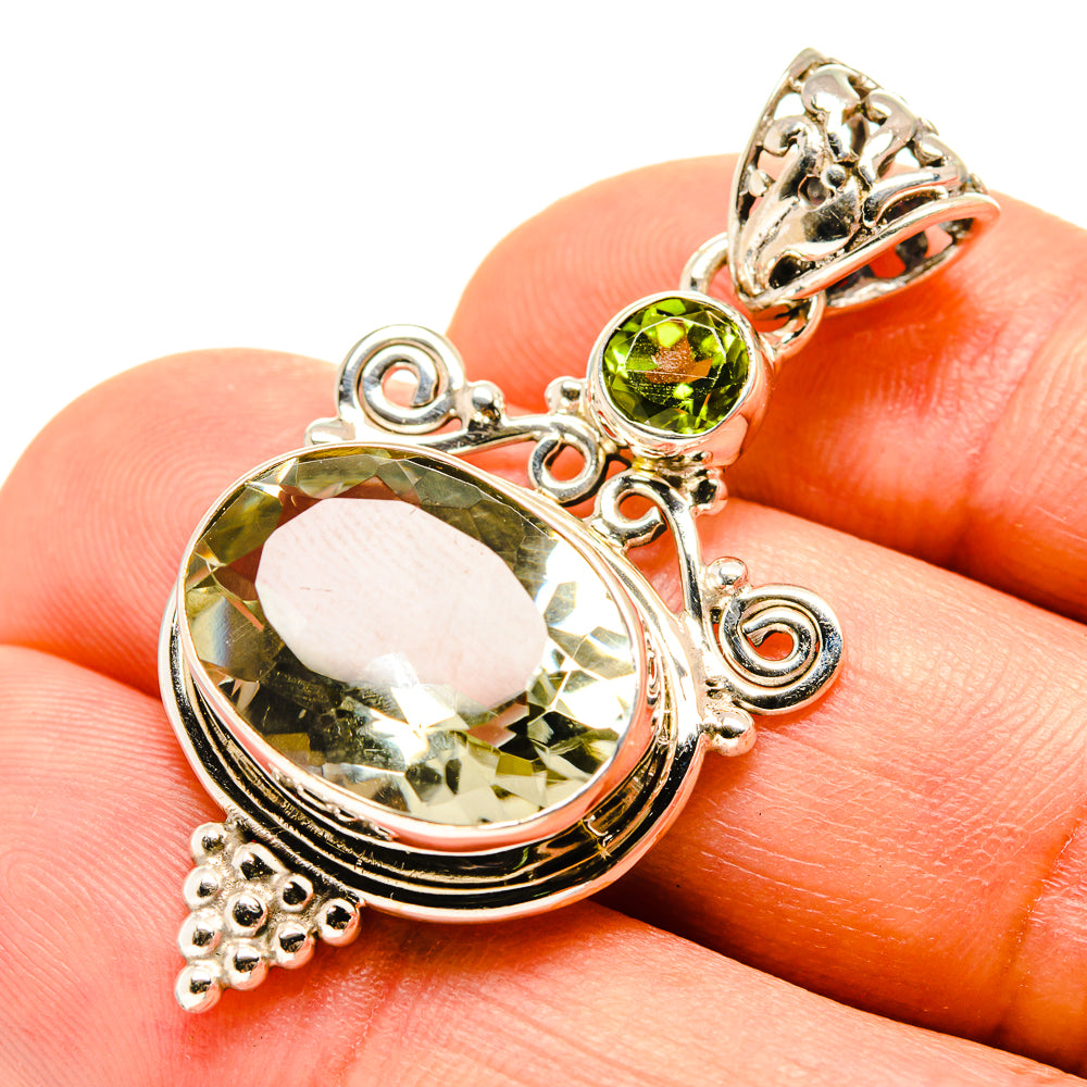Faceted green stone pendant with circular peridot bead and ornate silver side scrolls