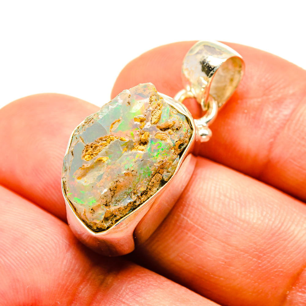 Rough opal pendant in sterling silver, faceted bezel with rainbow speckled stone