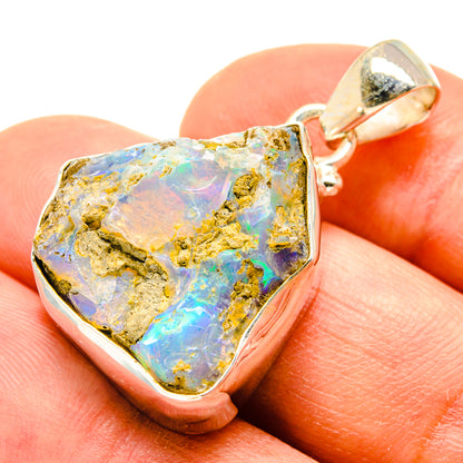 Rough opal pendant on finger, silver bail and bezel with blue, yellow, pink highlights