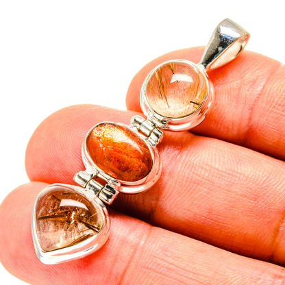 Gemstone pendant close-up with orange sunstone and clear rutilated hearts in silver bezels