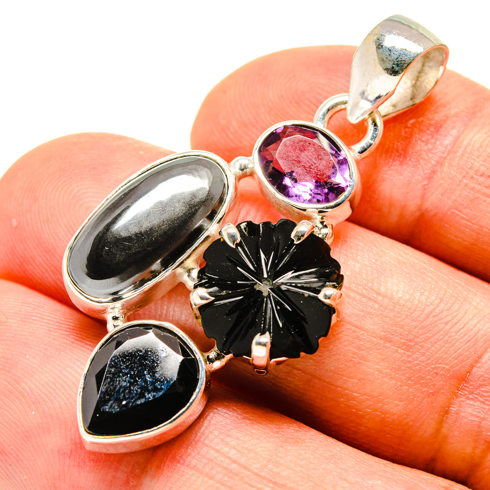 Sterling silver pendant with purple gemstone, black oval stones, and black flower motif bail