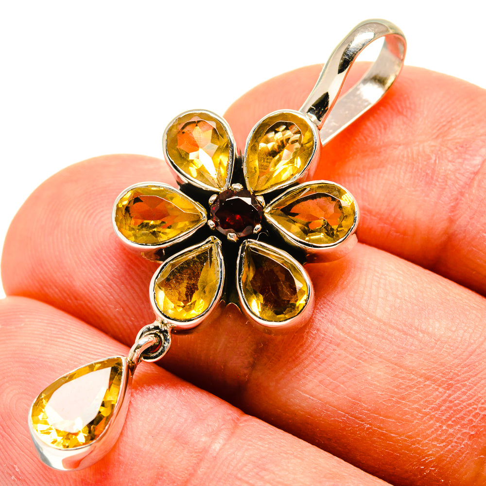 Sterling silver flower pendant with faceted yellow stones, dark center, dangling teardrop.