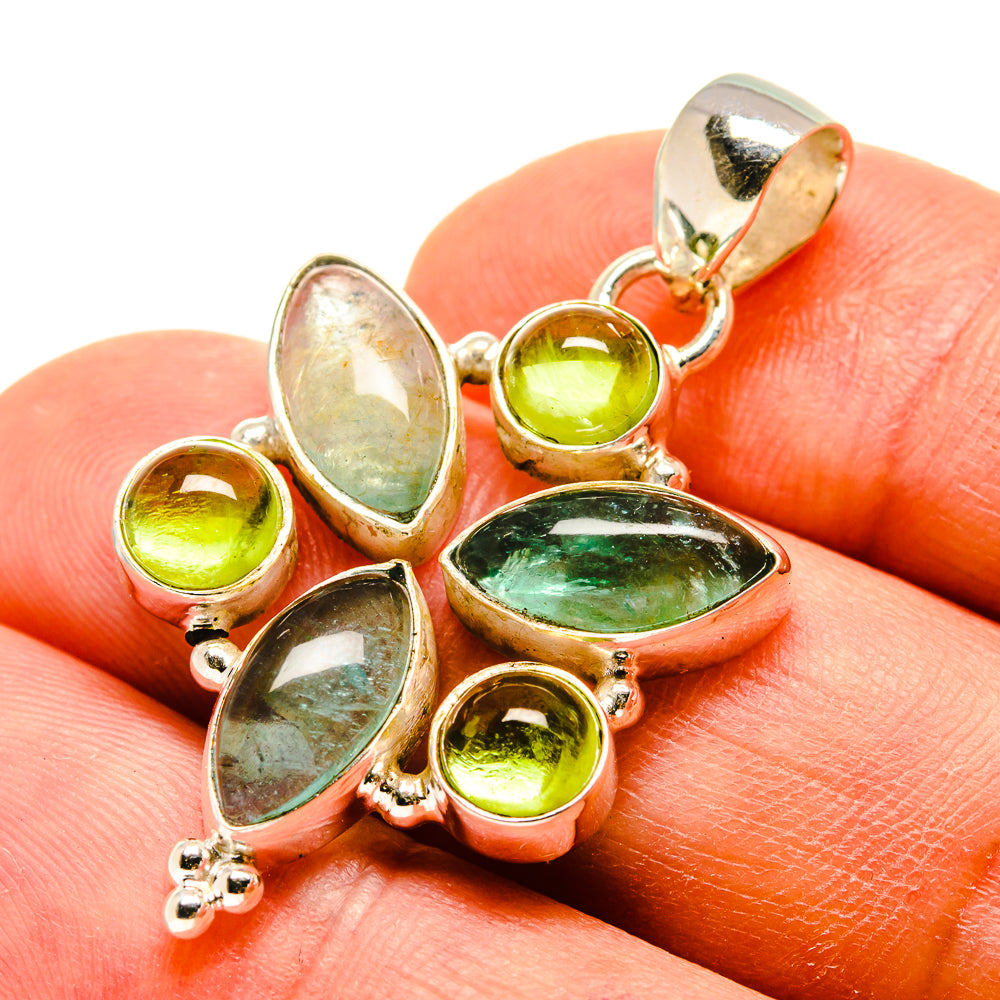 Gemstone pendant with silver prongs and mixed green stones, shown on a finger