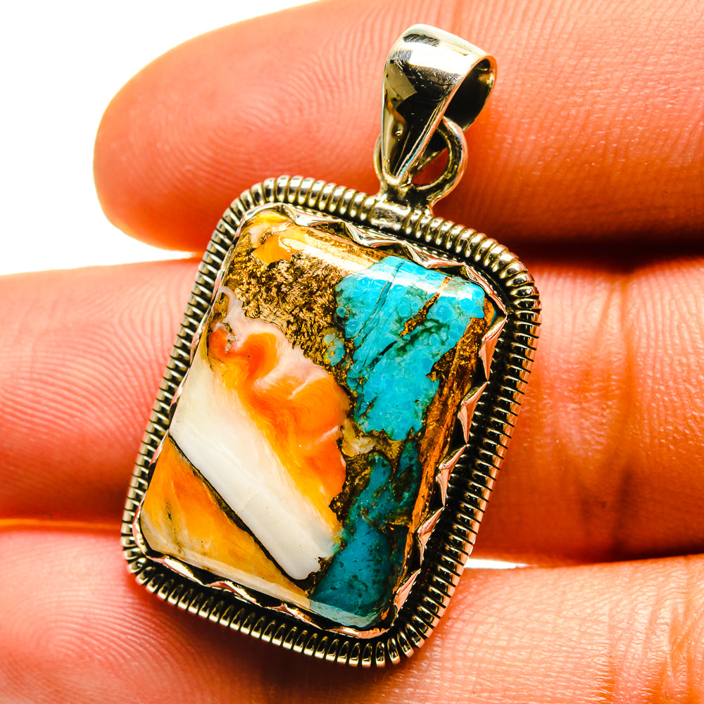 Turquoise, orange, and white stone pendant close-up on silver frame and bail