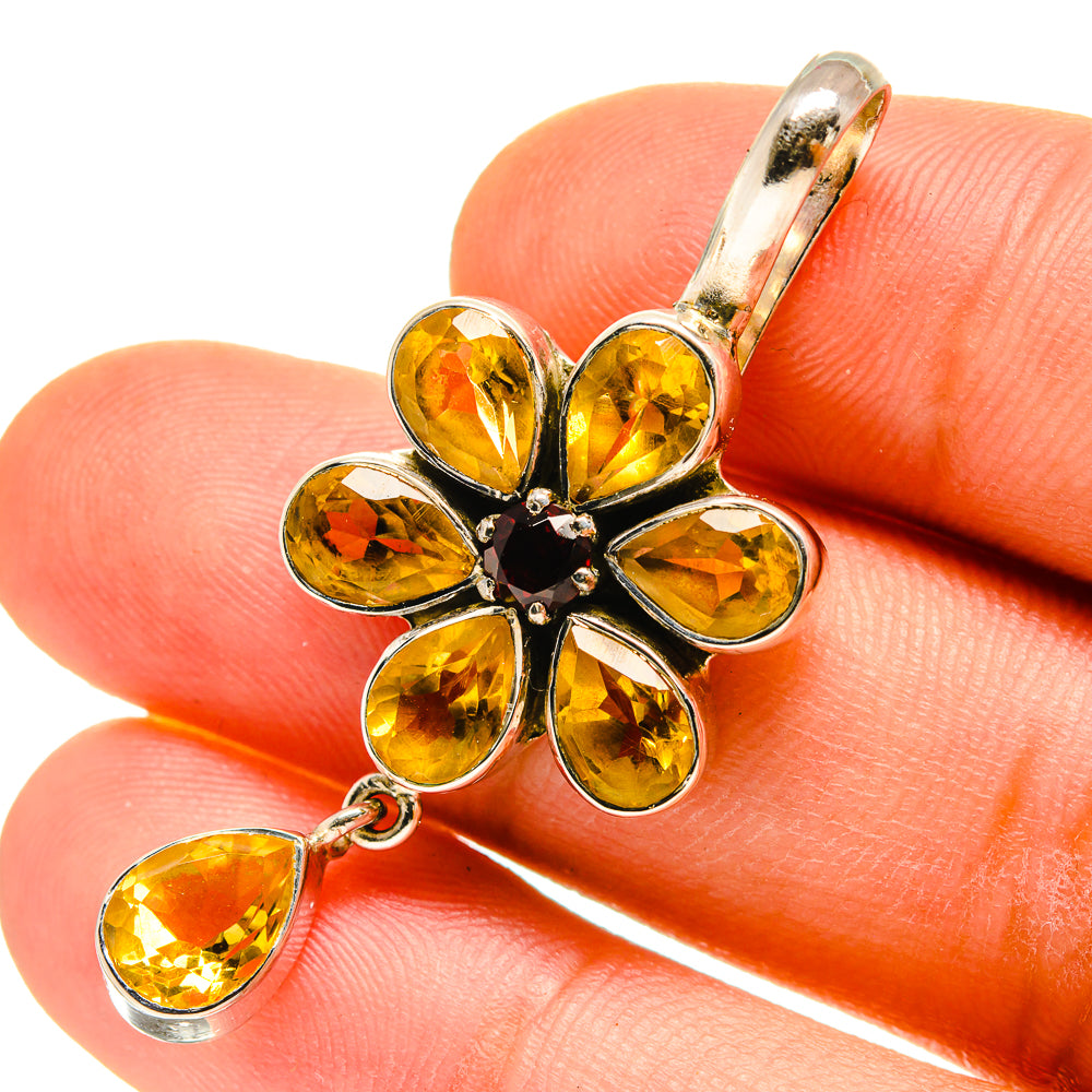 Sterling silver flower pendant close-up on hand, faceted yellow stones and dark center, drop charm