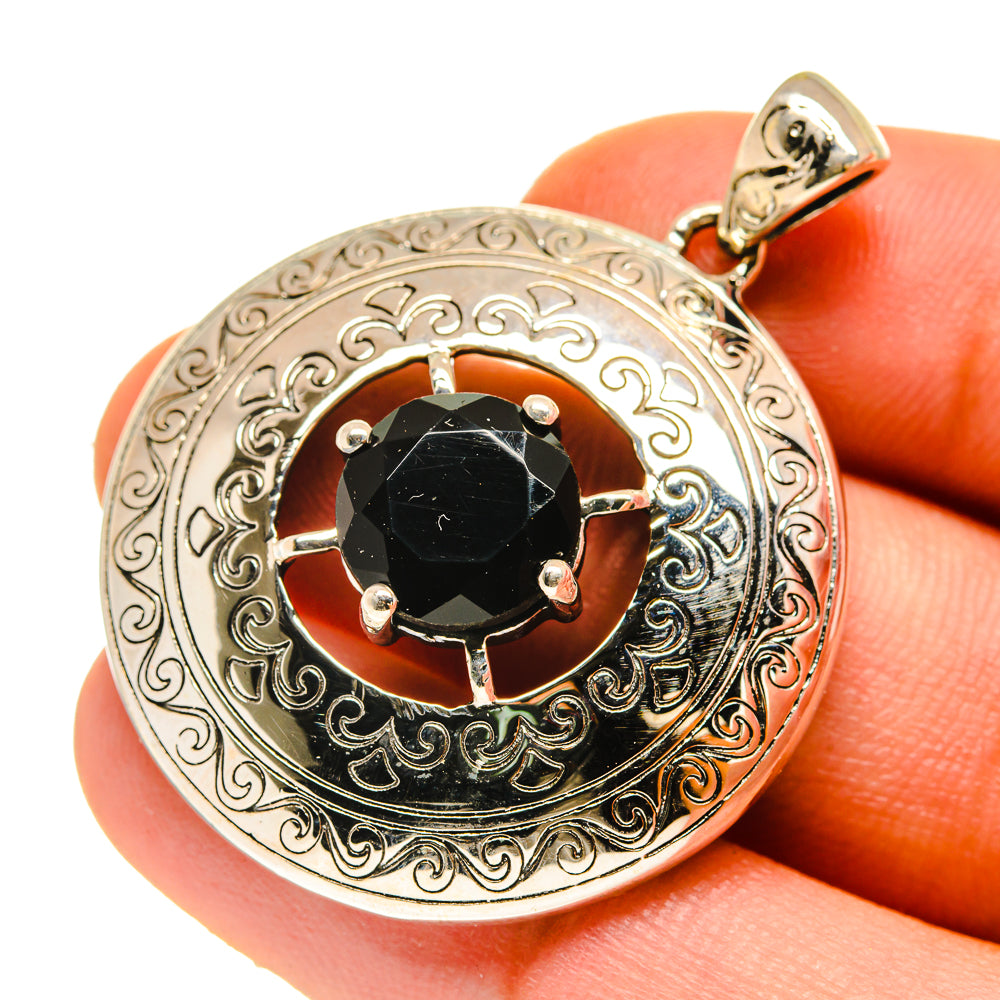 Close-up round black onyx pendant with engraved silver frame, prongs around stone, bail loop