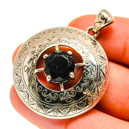 Close-up round black onyx pendant with engraved silver frame, prongs around stone, bail loop