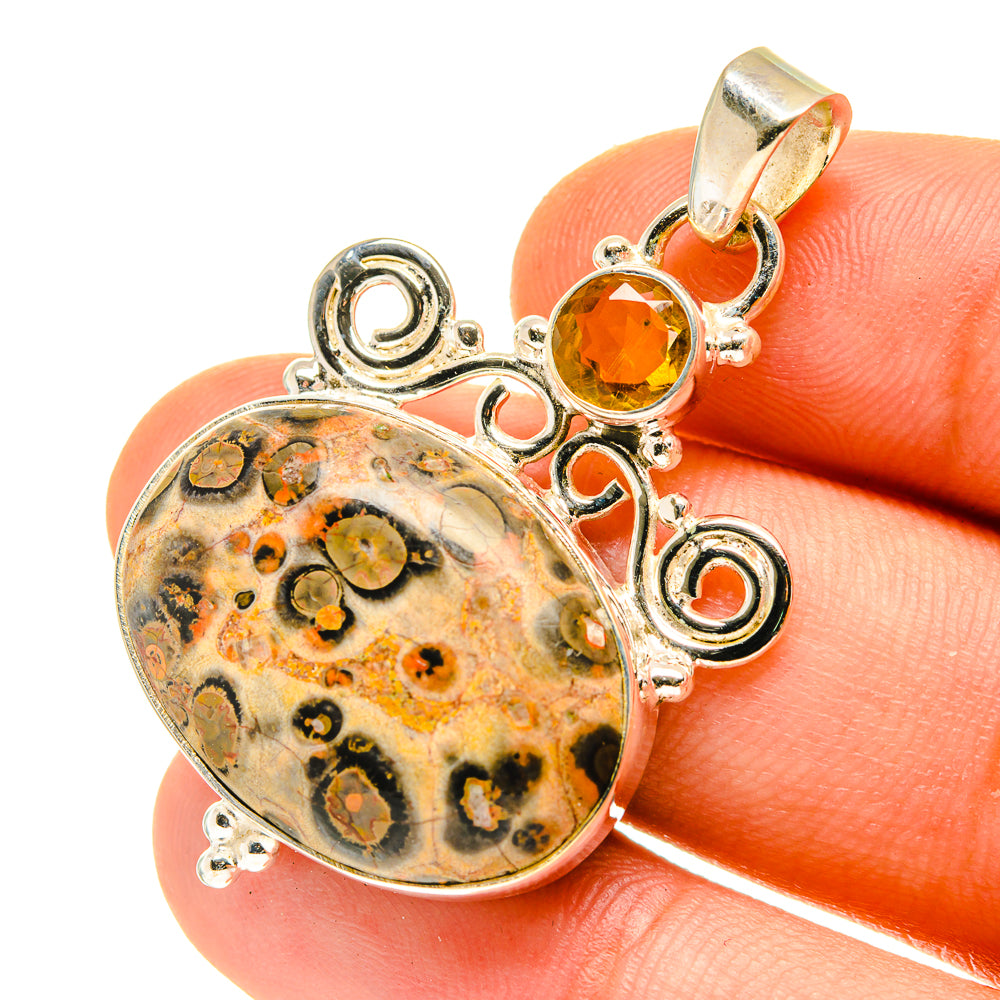 Oval poppy jasper and round citrine sterling silver pendant on fingertip