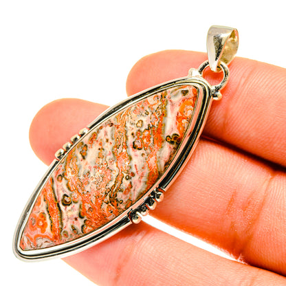 Orange poppy jasper teardrop pendant in sterling silver with bail, shown on finger