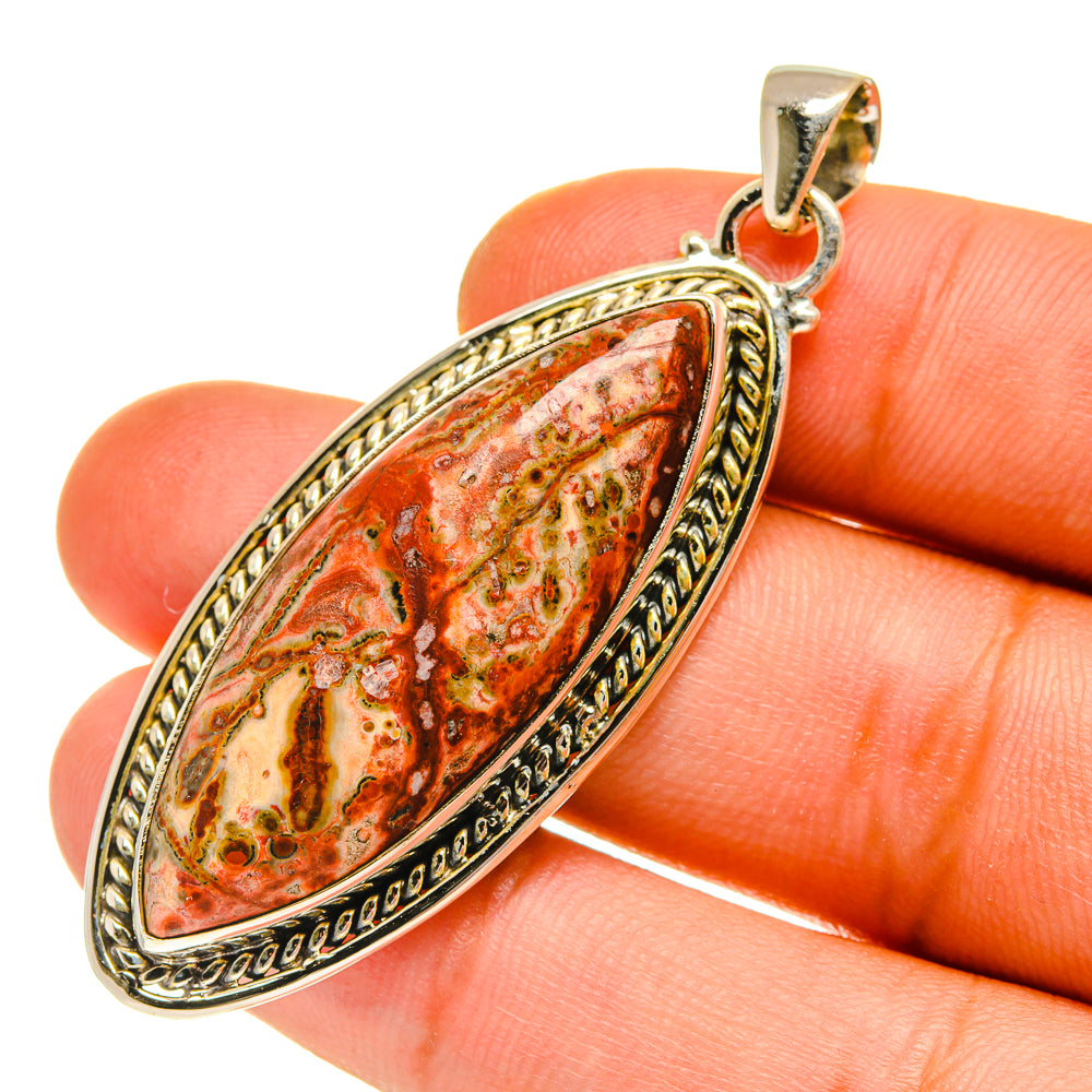 Red jasper teardrop pendant in ornate 925 sterling silver setting, on fingertip