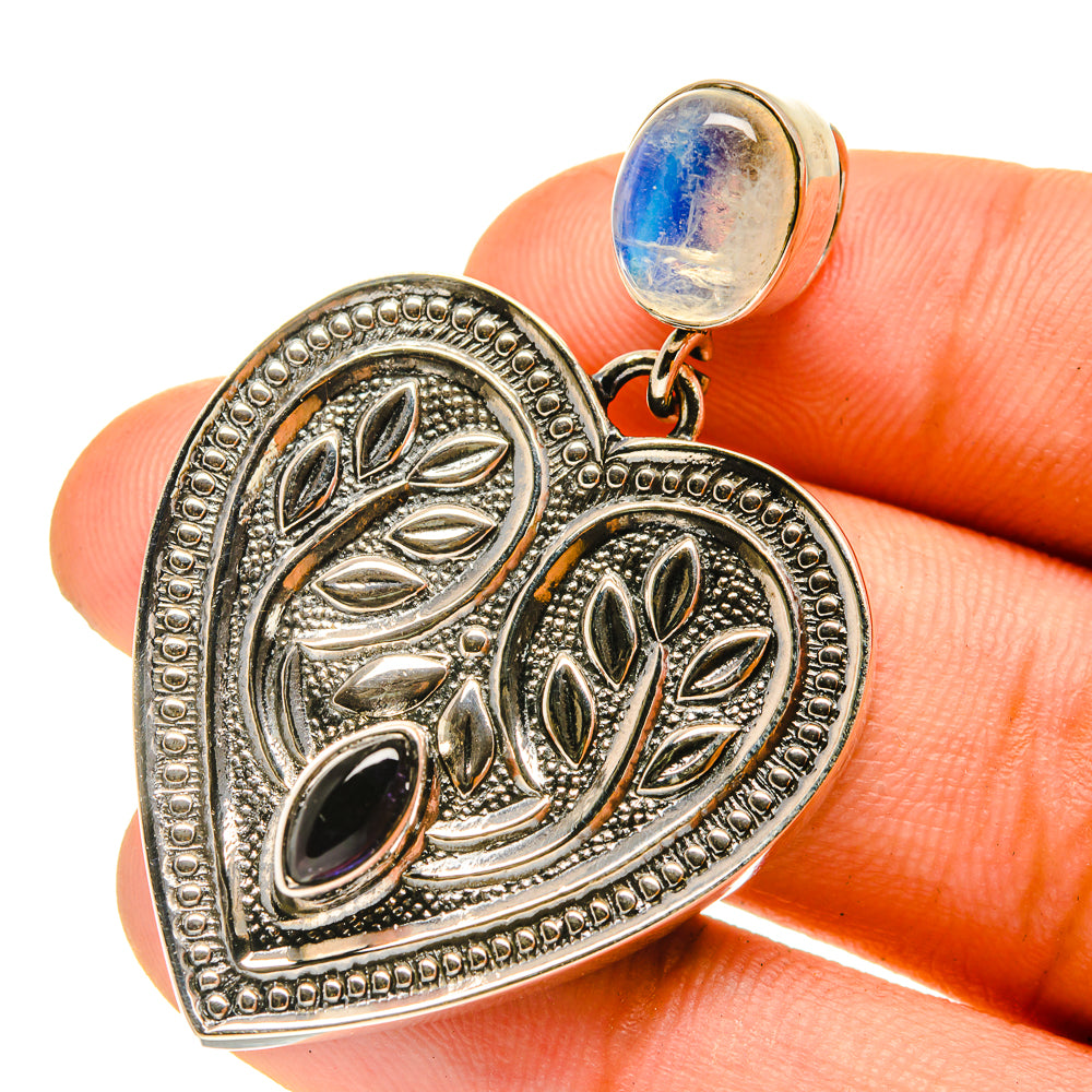 Heart-shaped silver-tone pendant with leaf filigree, dark oval and blue cabochon bail