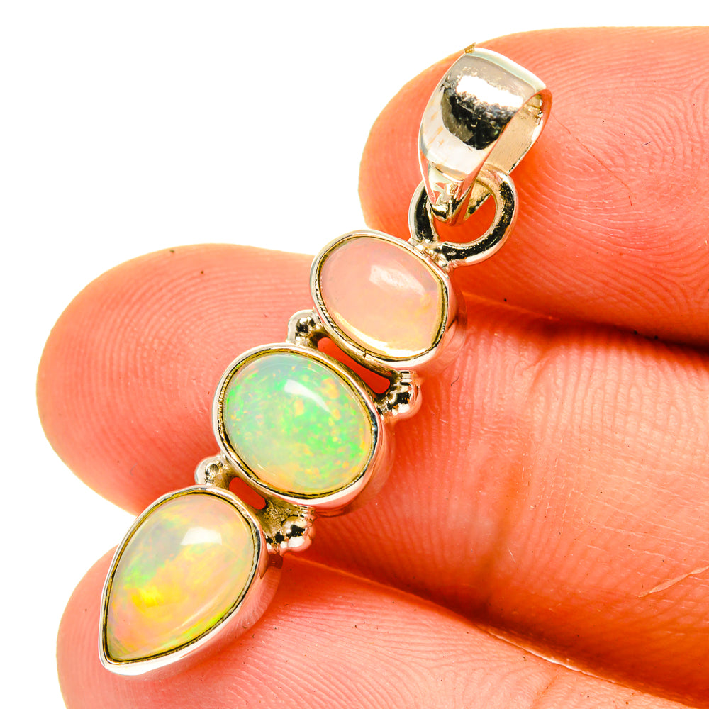 Gold-tone pendant close-up with three oval opal stones, green and yellow color play