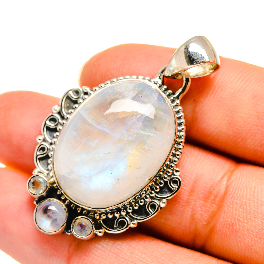 Oval rainbow moonstone pendant in sterling silver with ornate bezel and small round accents