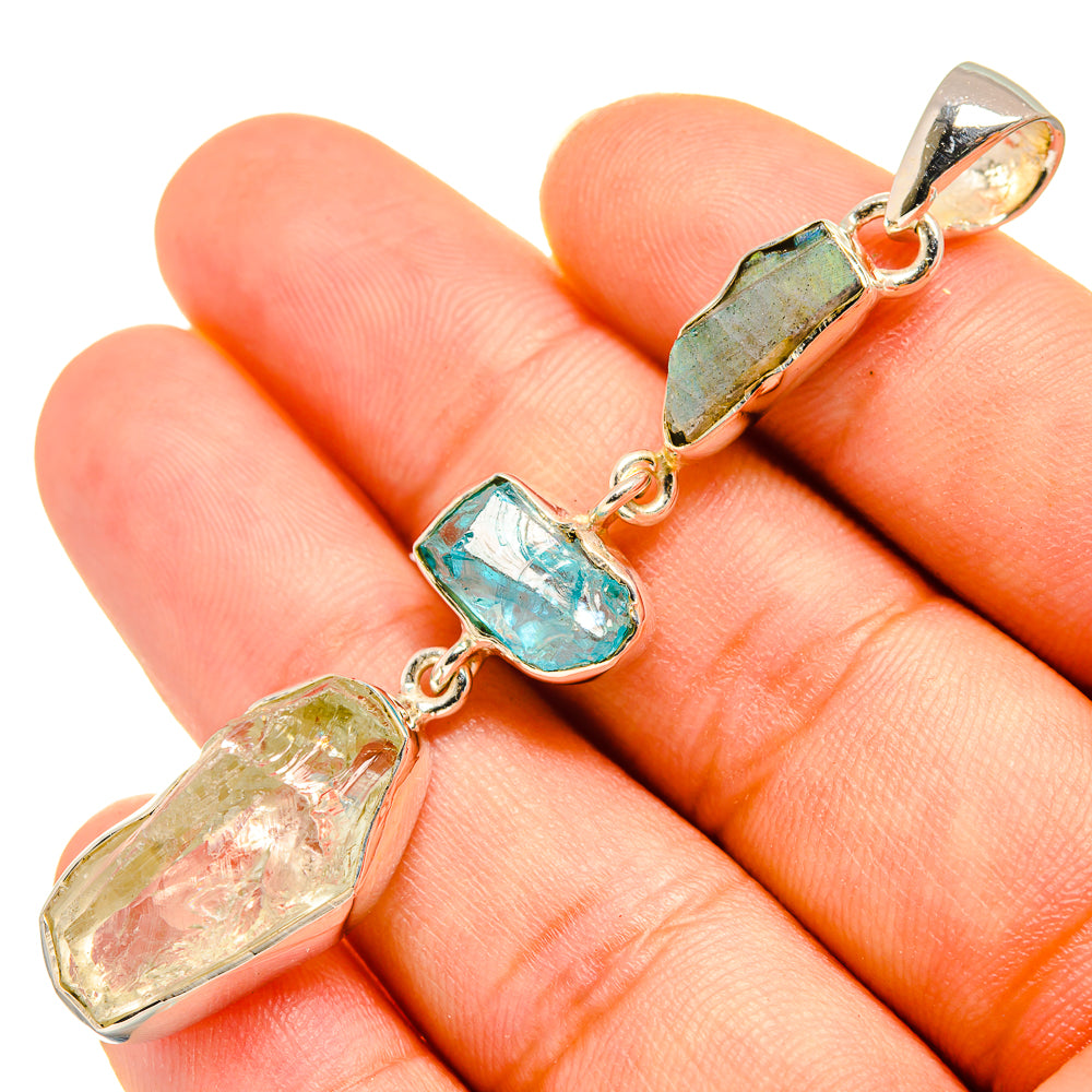 Sterling silver pendant on hand with rough turquoise, green, and light yellow gemstones