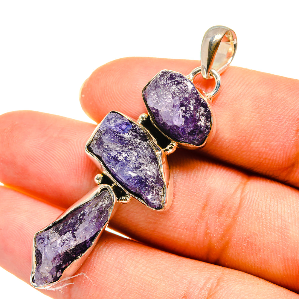 Rough tanzanite pendant close-up on hand: three purple rough stones, gold-tone 925 silver