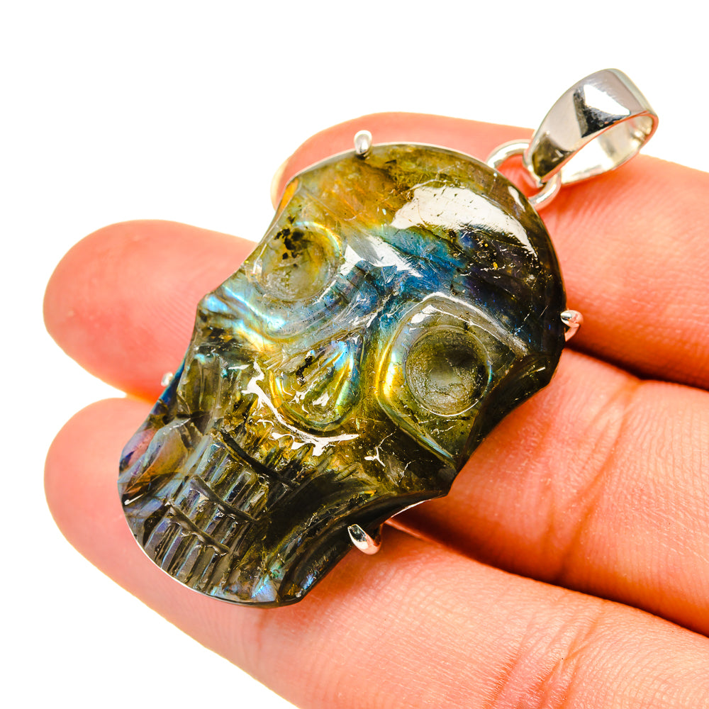 Labradorite skull pendant close-up, yellow stone with blue and green iridescence, silver bail