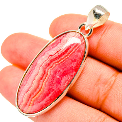 Oval pink rhodochrosite pendant close-up, silver frame and ridged stone in center