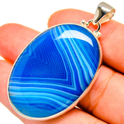 Blue agate pendant in sterling silver bezel, held on finger; top bail visible
