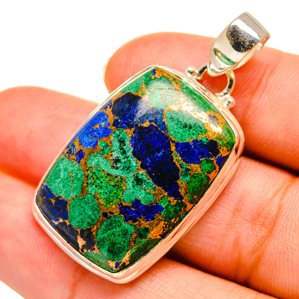 Sterling silver oval pendant with multicolor azurite-style stone on finger close-up