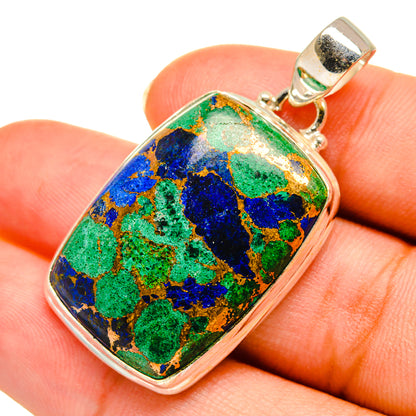 Sterling silver oval pendant with multicolor azurite-style stone on finger close-up