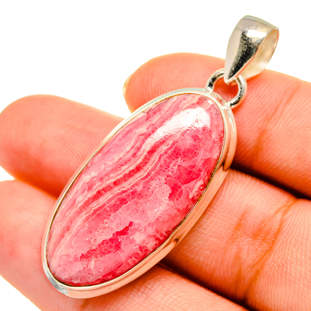 Rhodochrosite pendant on hand, oval red-pink stone with sterling silver bail