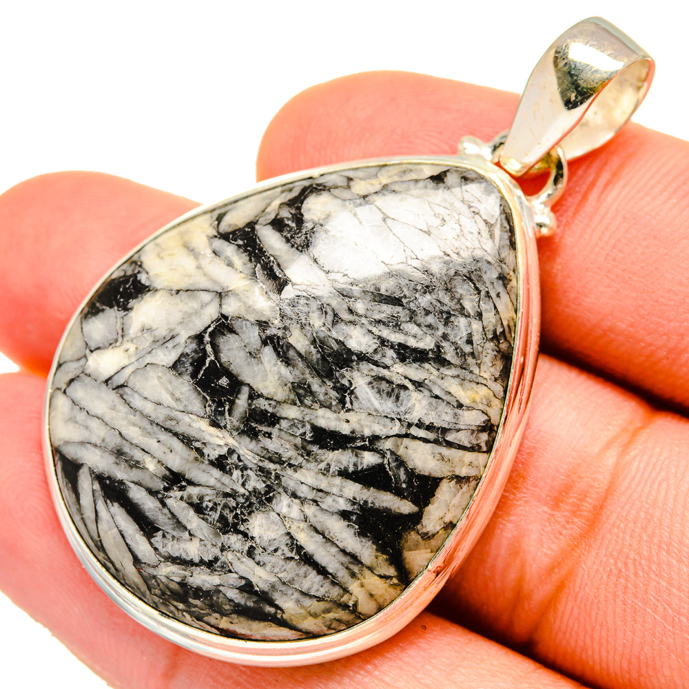 Teardrop stone pendant with black-and-white chrysanthemum stone, gold-tone bail, on finger