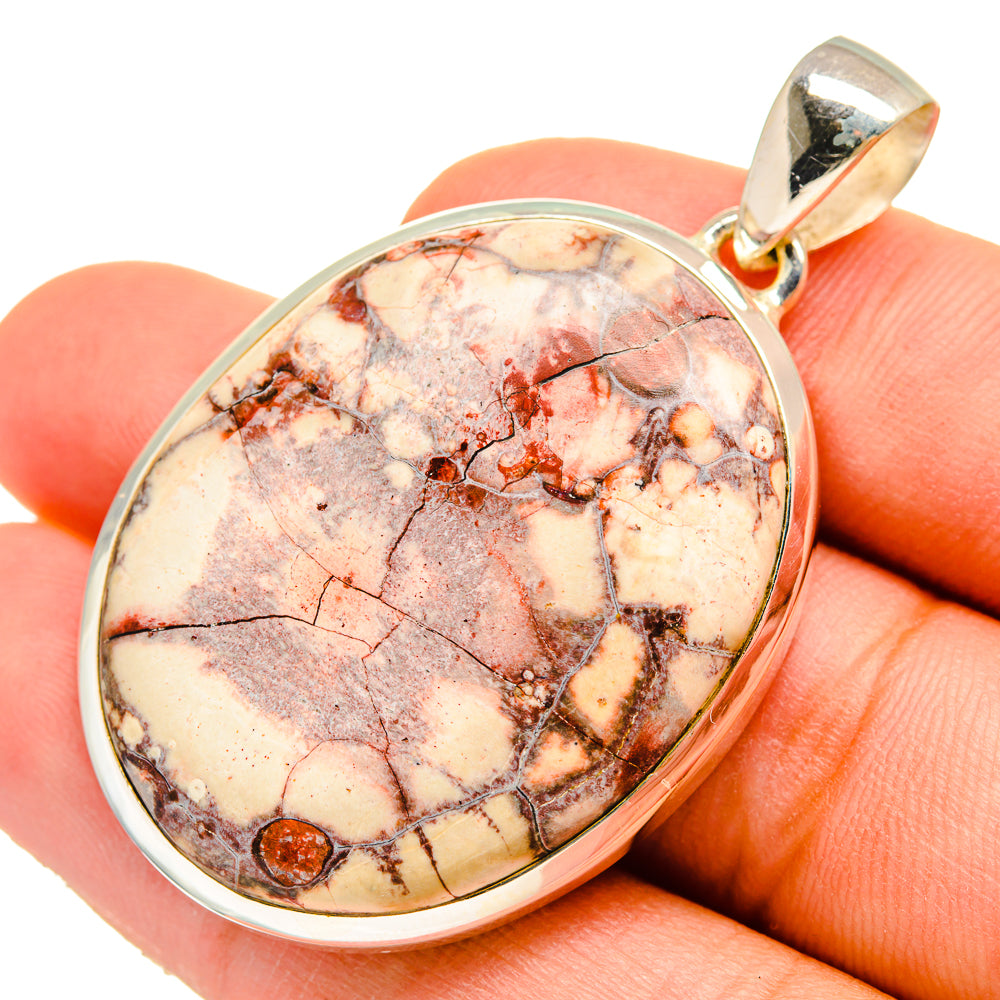 Sterling silver pendant with oval poppy jasper cabochon, warm cream and red mottling.