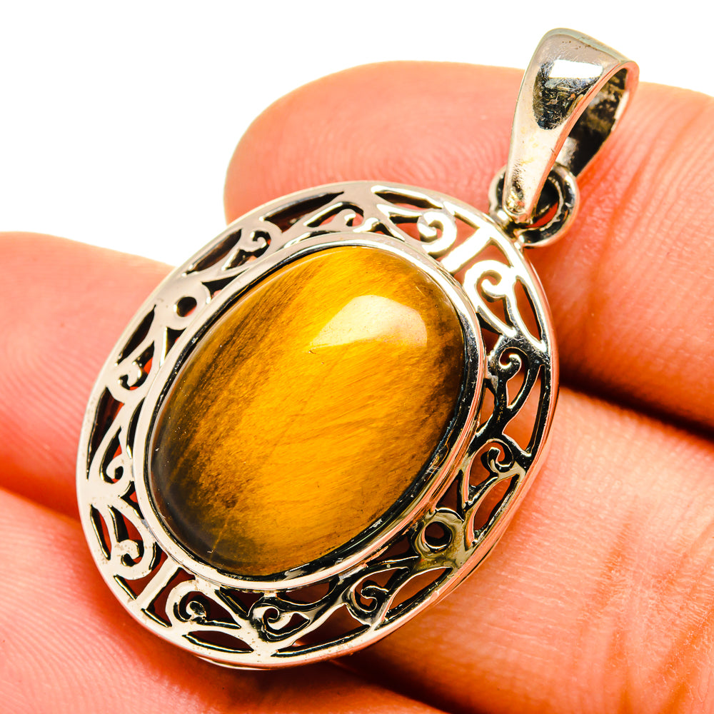 Tiger eye pendant on silver bail, oval amber-gold stone in engraved filigree frame.