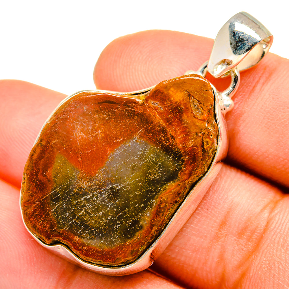 Heart-shaped petrified wood pendant in amber and green with silver bezel and bail