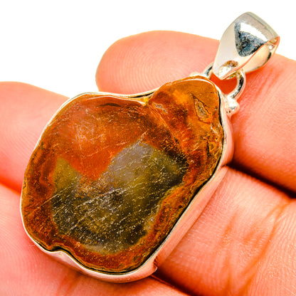 Heart-shaped petrified wood pendant in amber and green with silver bezel and bail