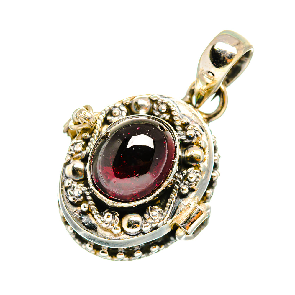 Round sterling silver pendant with dark red gemstone, ornate bezel and bail loop.