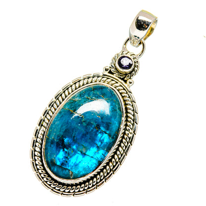 Ornate oval blue gemstone pendant in sterling silver with small purple stone at top.