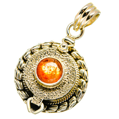 Round sunstone pendant with engraved swirl frame and orange cabochon, gold-toned bail