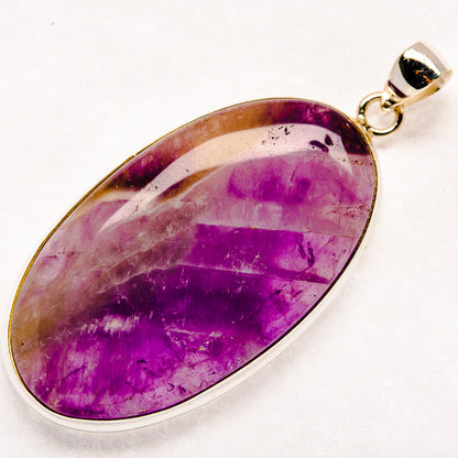 Oval purple chevron amethyst pendant in sterling silver bezel with loop bail.