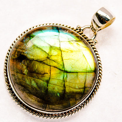 Round labradorite pendant with vivid green flashes in textured silver bezel and bail