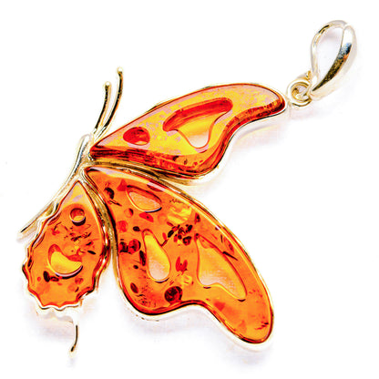 Amber butterfly pendant with silver-tone frame and small marbled orange wings, bail loop