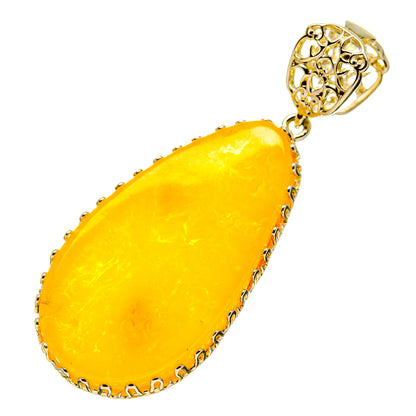 Teardrop yellow amber pendant with ornate gold-toned silver cap and loop