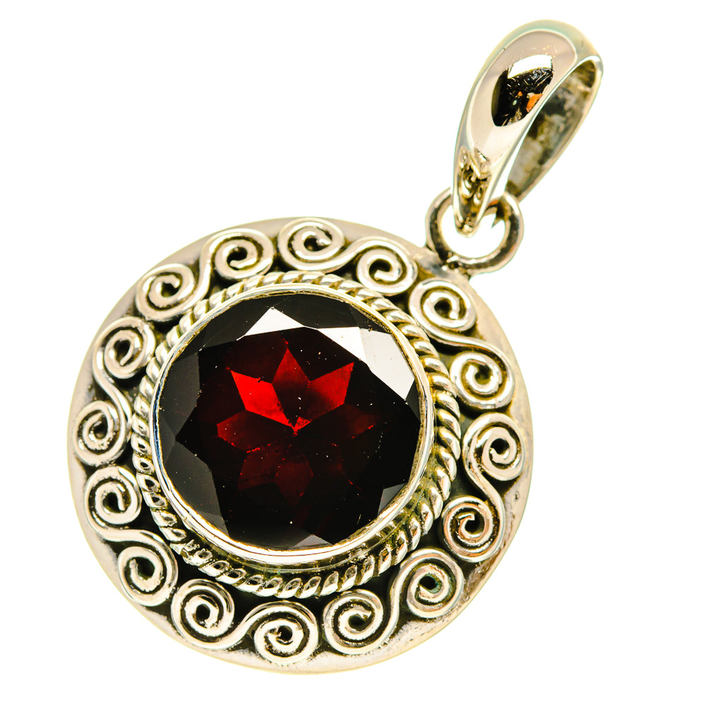 Round sterling silver pendant with ornate scroll frame and dark faceted gemstone with red