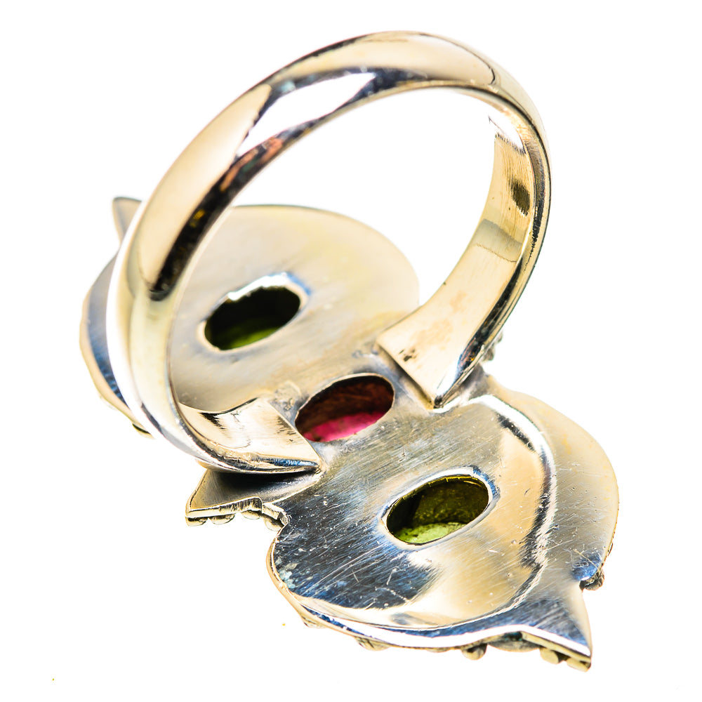 Sterling silver ring underside with cutout openwork and hints of green and pink gemstones.