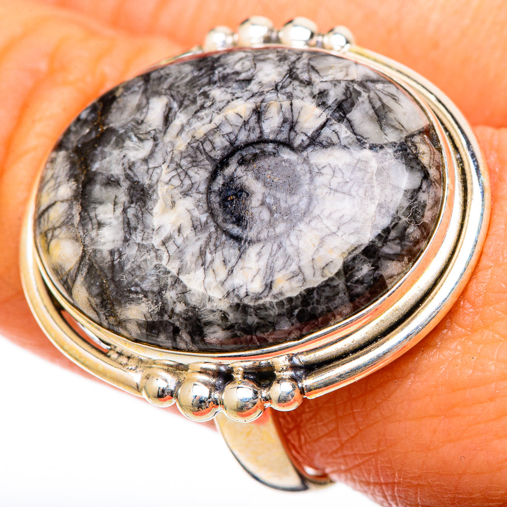 Sterling silver ring on hand, oval fossil face with black spiral, round bead halo