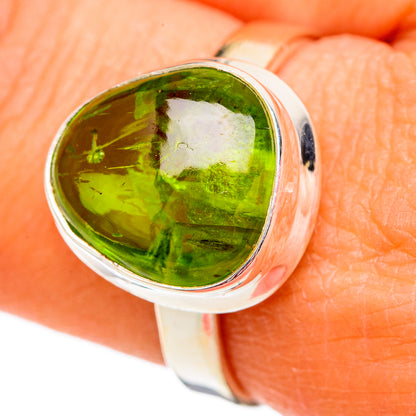 Sterling silver ring with oval green peridot gemstone, close-up on reflective bezel