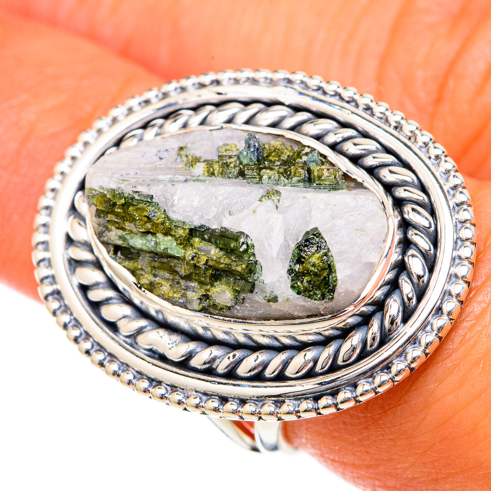 Green tourmaline in quartz oval ring, textured twisted silver band on finger.