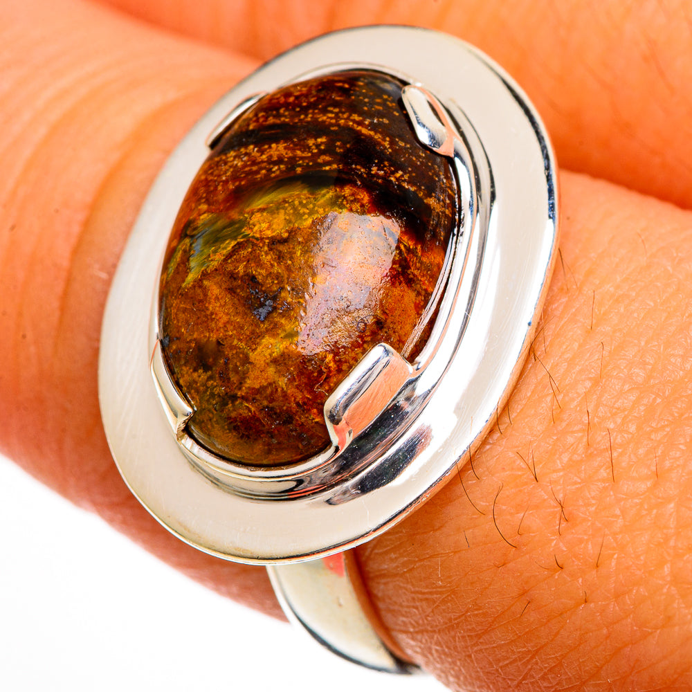 Sterling silver oval pietersite cabochon ring on finger, amber-brown stone