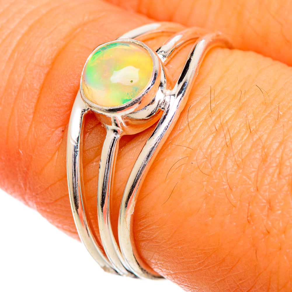 Ethiopian opal sterling silver ring, close-up of round iridescent stone on finger