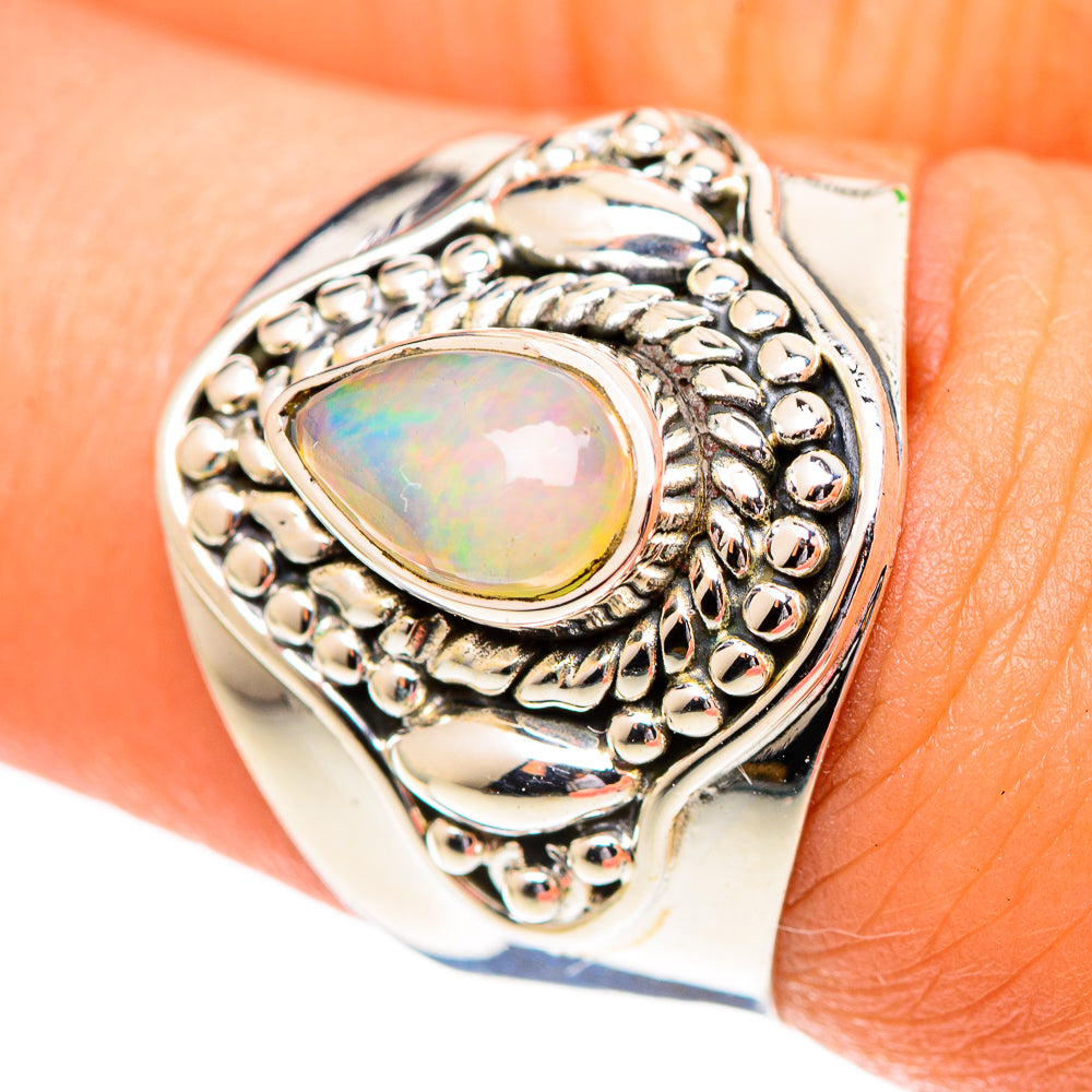 Sterling silver opal ring on finger with oval cabochon and scalloped filigree bezel