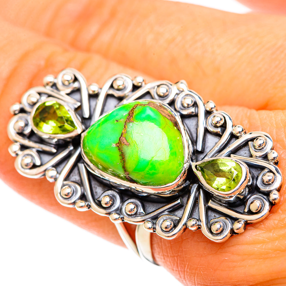 Green gemstone ring close-up with bezel-set oval center and small side stones, silver